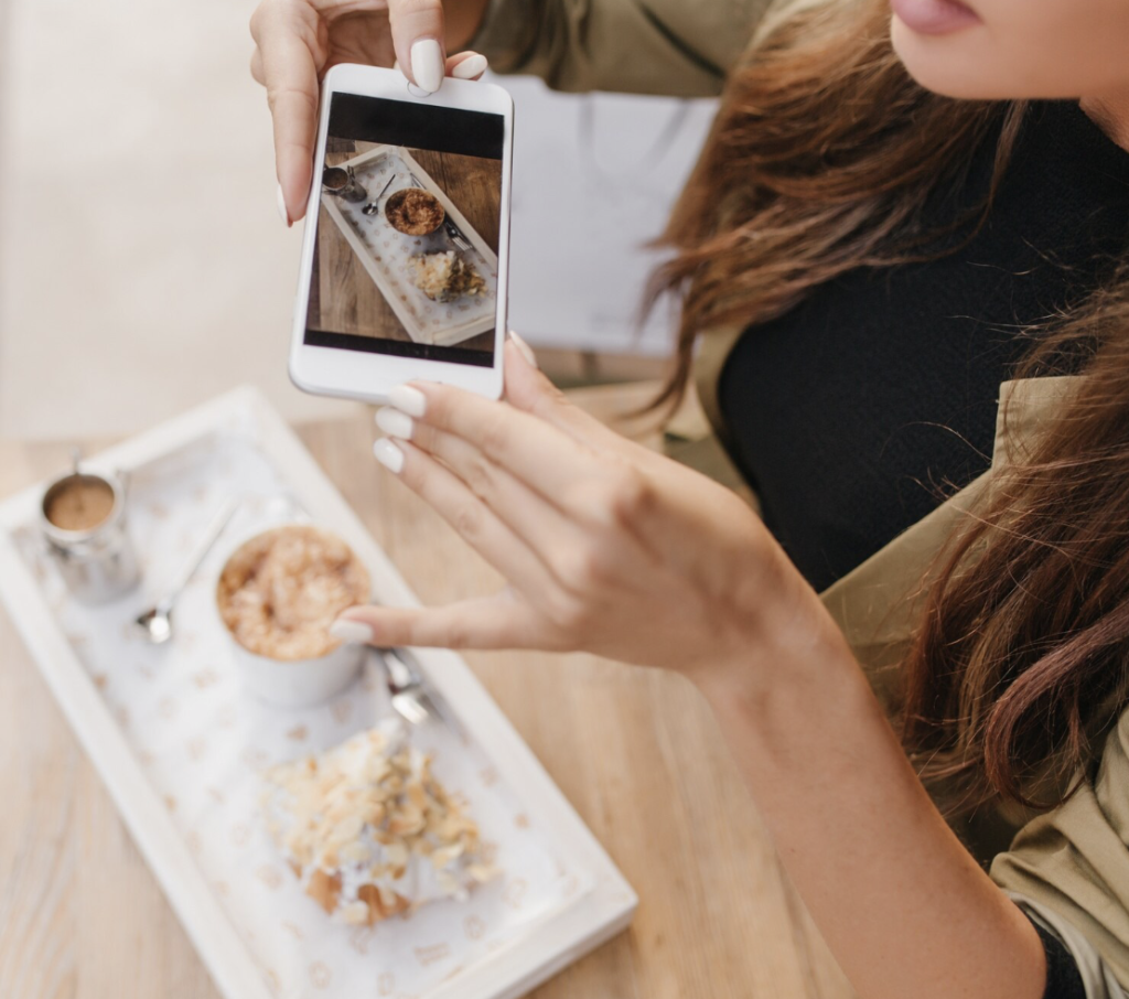 Dame som tar bilde av maten sin på en kafe med en iPhone
